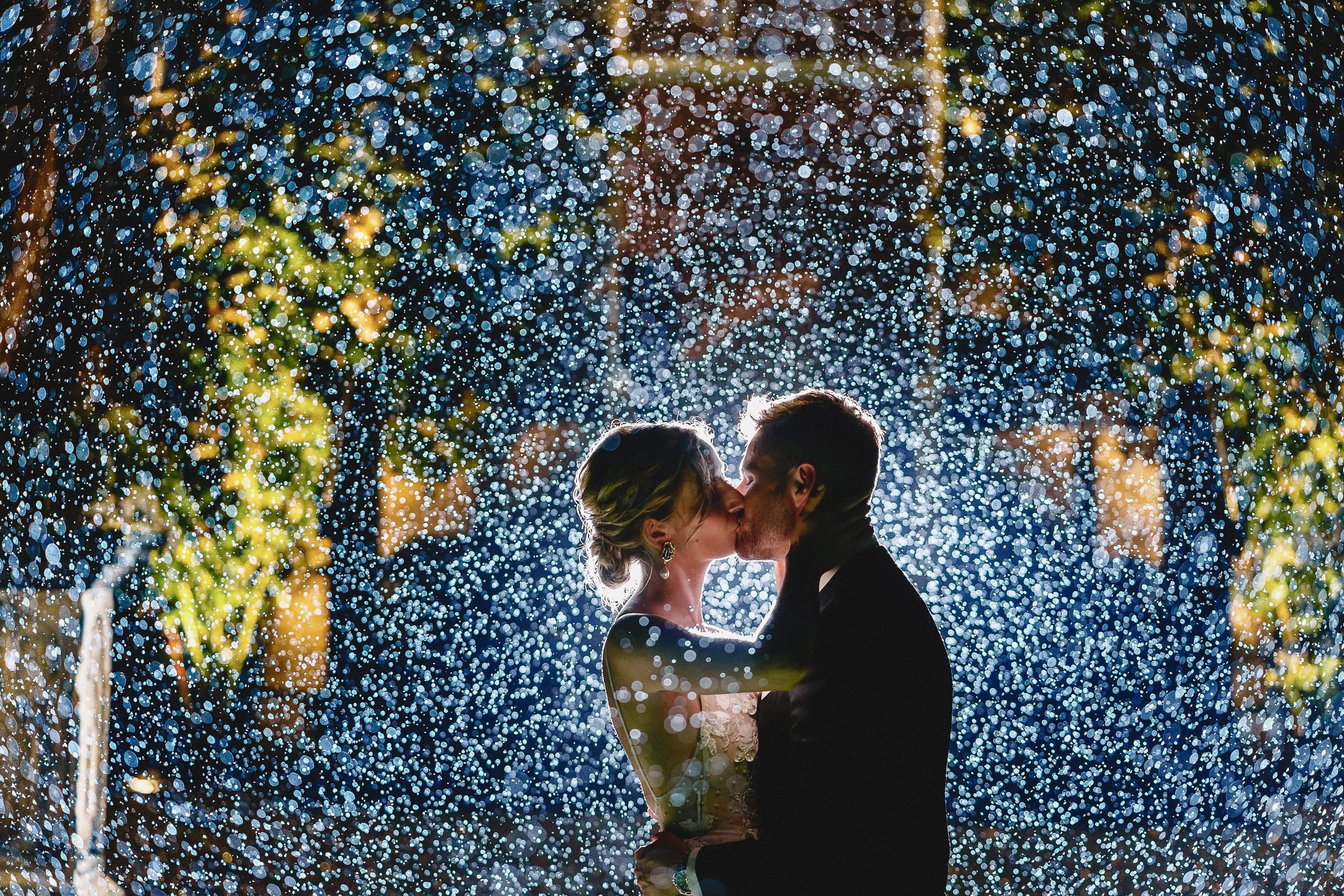 bride and groom kissing in the rain at night