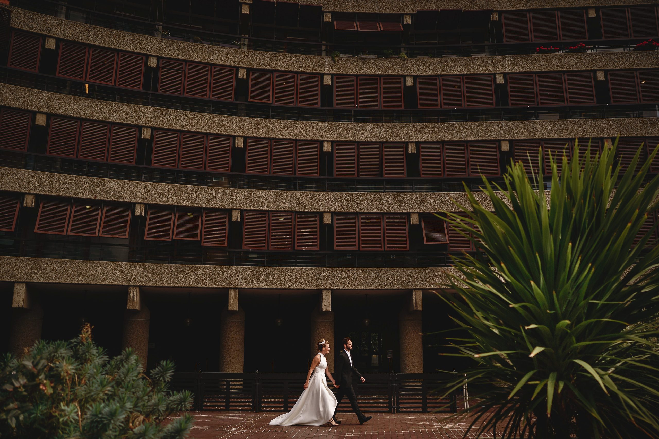 Bride and groom outside the barbican walking - brutalist architecture